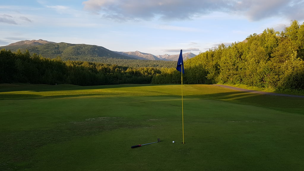 photo of a flagstick, with fairway and mountains in the background.